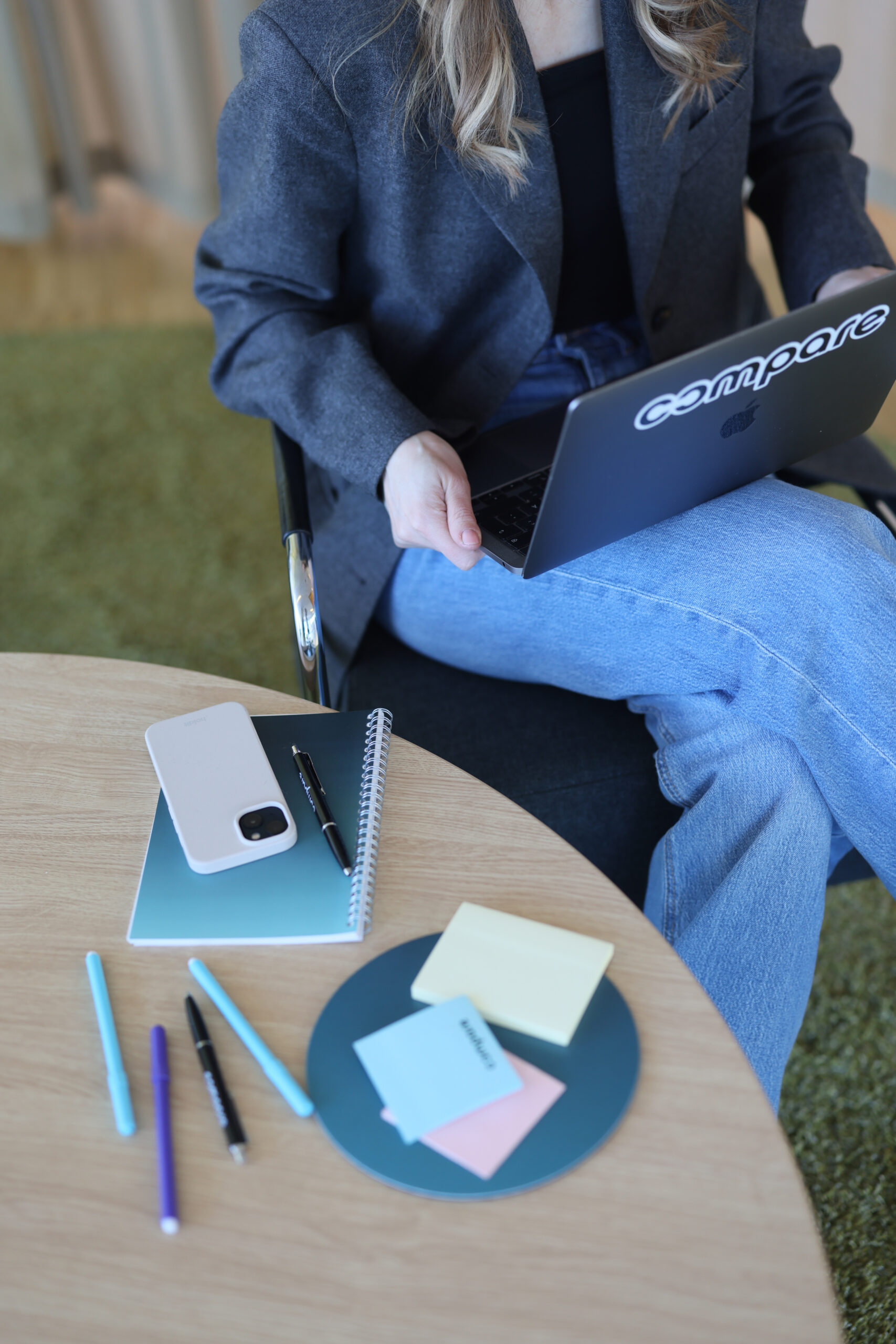 Person sitter vid bord med laptop, penna och papper