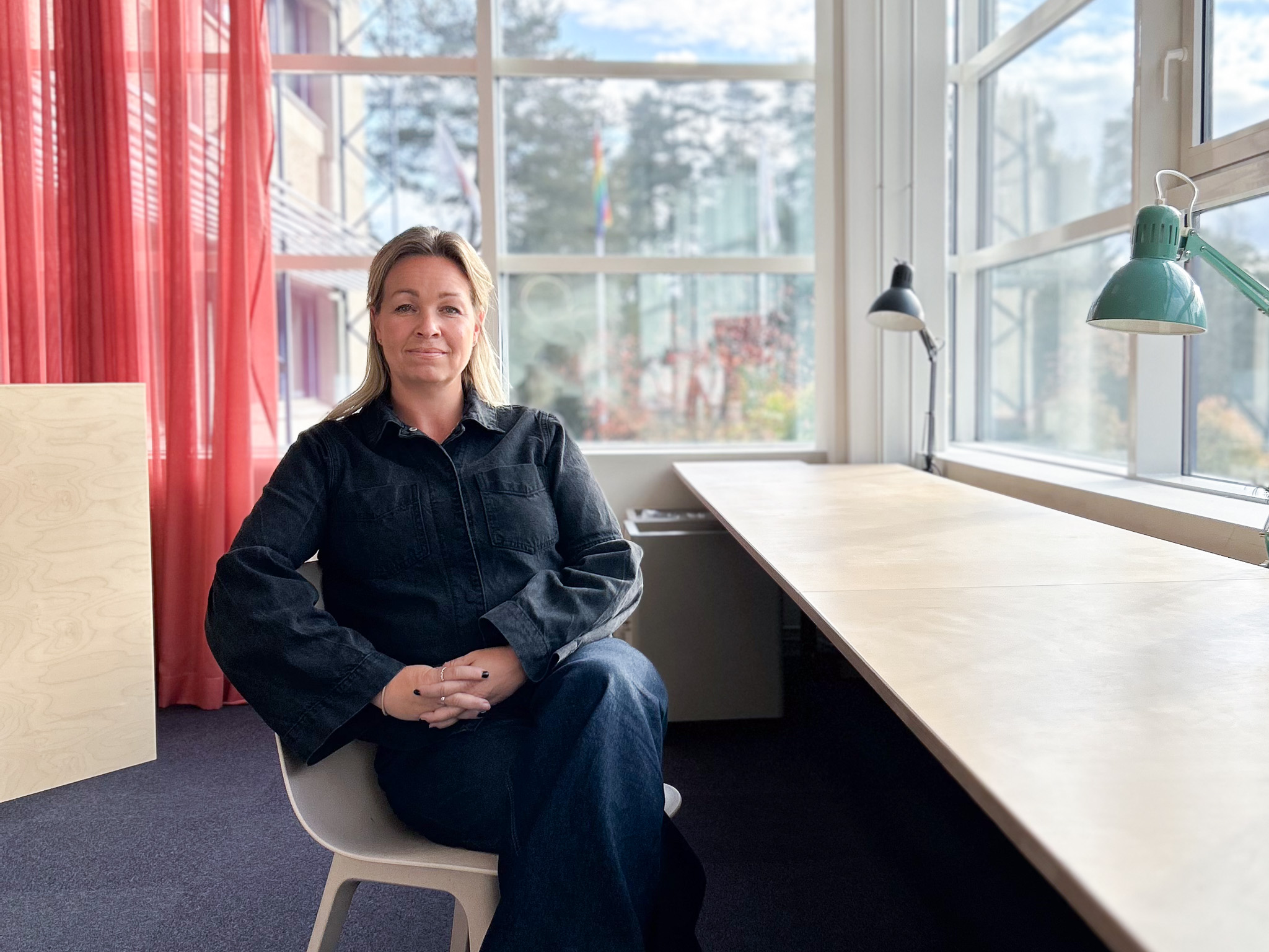 Ljushårig kvinna med mörka kläder sittandes på stol.