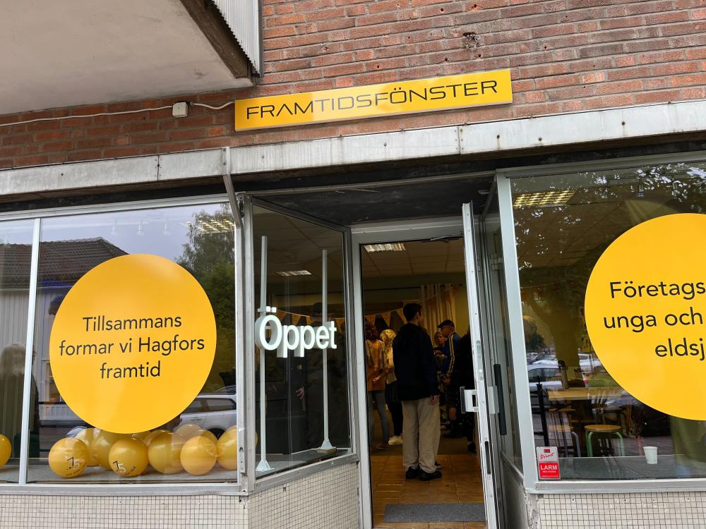 En tegelbyggnad med stora glasfönster och en öppen dörr. Över dörren står det Framtidsfönster.